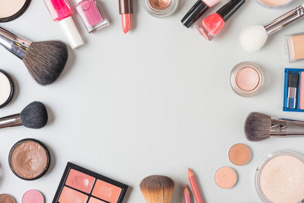 Overhead view of various makeup products forming circular shape on white background