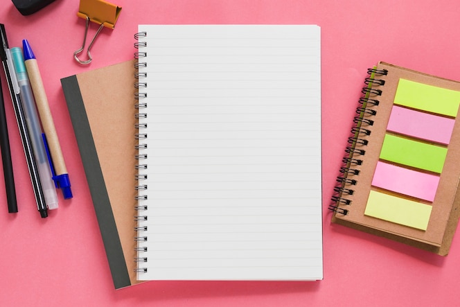 Overhead view of various stationeries on pink background