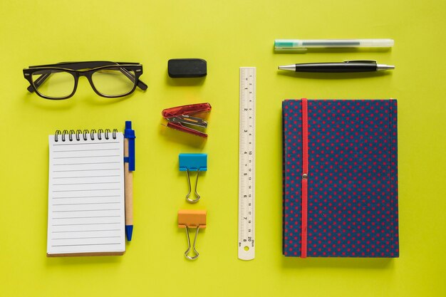 Overhead view of various stationeries on yellow background