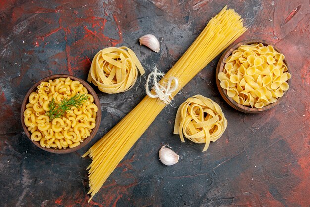 Overhead view of various types of uncooked pastas on mixed color table 