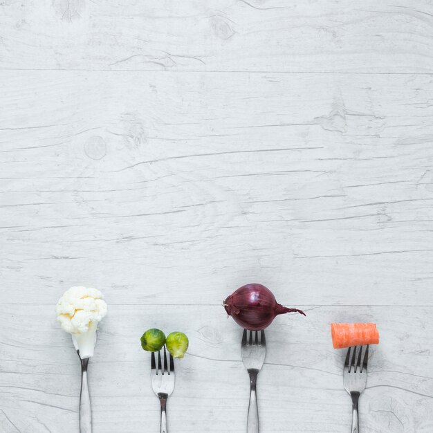 An overhead view of vegetables on fork arranged on wooden table