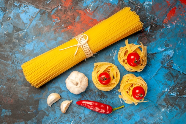 Overhead view of vermicelli noodles tied with ropes and peppers garlic on blue background