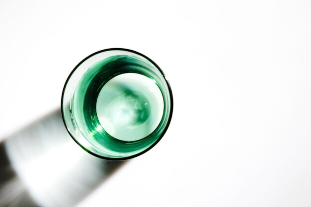 An overhead view of water in the green glass on white background