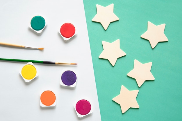 Free photo overhead view of watercolor paints; paintbrush and star shape on dual colorful background