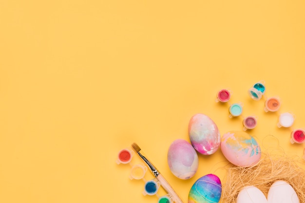 An overhead view of watercolor in the plastic bottle; easter eggs on the corner of yellow background