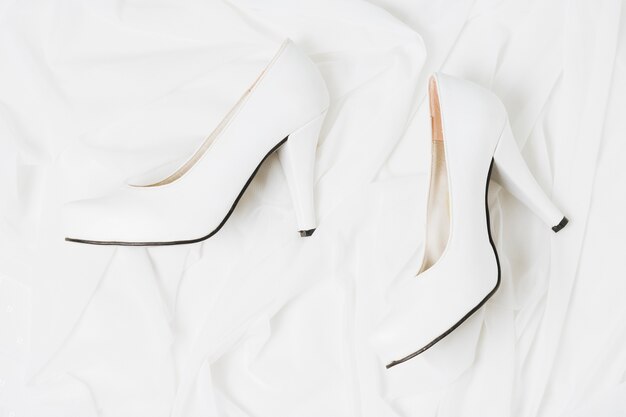 Вид сверху на свадьбу белые высокие каблуки на белой ткани
