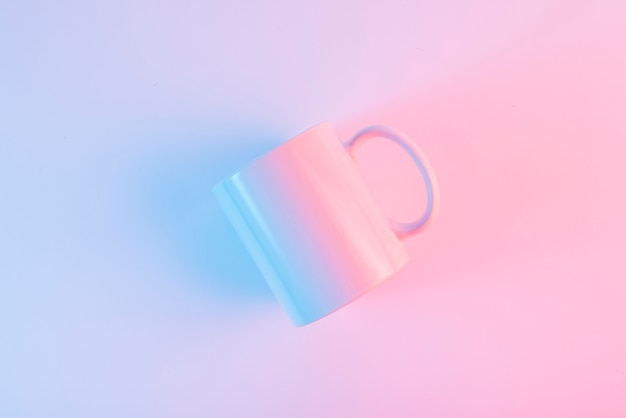 An overhead view of white ceramic mug against pink background