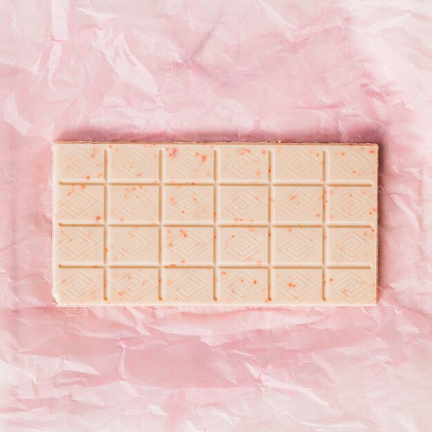 An overhead view of white chocolate bar on pink paper wrapper