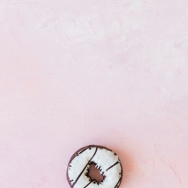 Free photo overhead view of white chocolate donut on pink backdrop