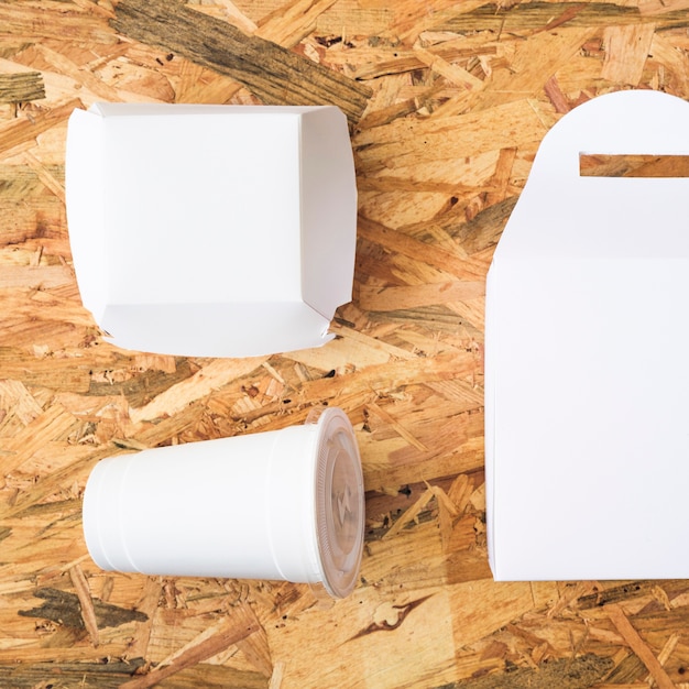 An overhead view of white takeaway food on wooden textured background