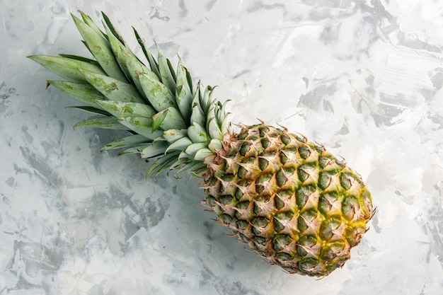 Overhead view of whole fresh golden pineapple on marble surface