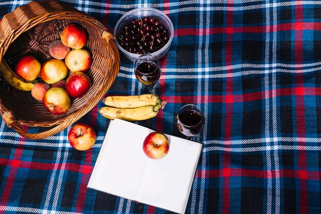 An overhead view of wine glasses; apple; banana and book on blanket
