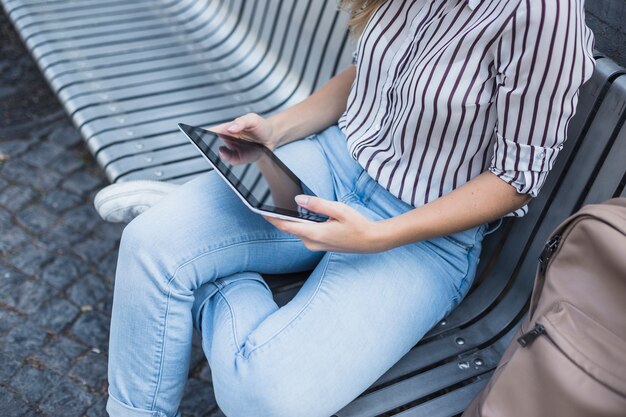 Overhead view of woman sitting on bench holding digital tablet