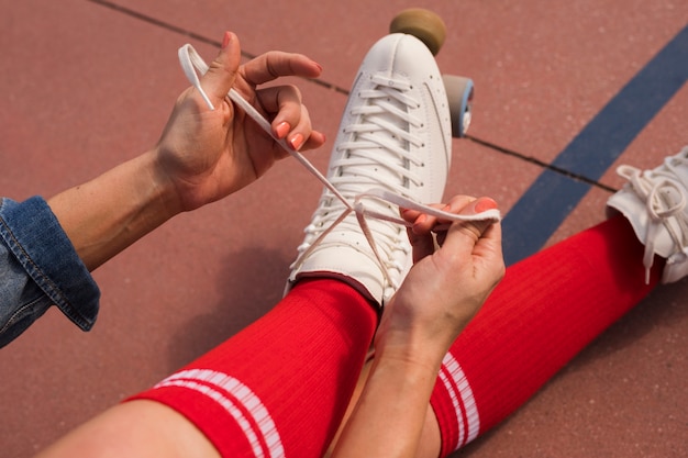 Free photo an overhead view of a woman sitting on ground tying the lace of roller skate