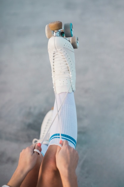 An overhead view of a woman tying the lace of roller skate