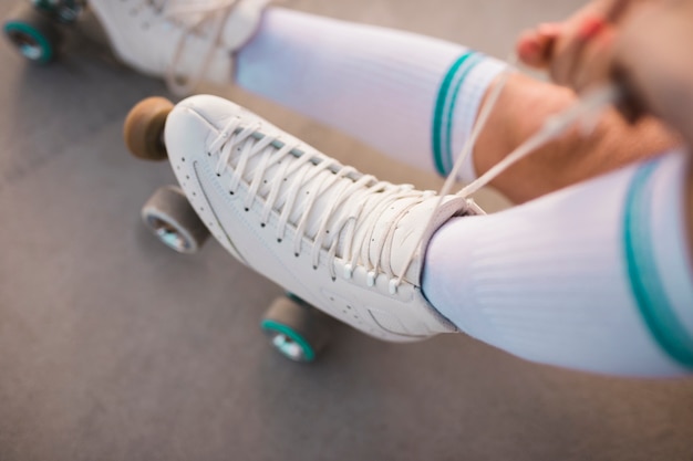 An overhead view of a woman tying roller skate lace