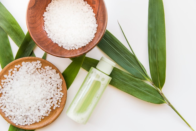 An overhead view of wooden plate with rock salts and organic lotion for beauty