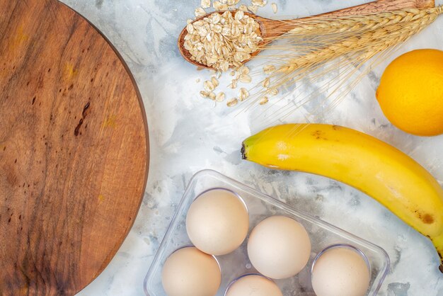 Overhead view of wooden round board and ingredients for the healthy food set on stained white table