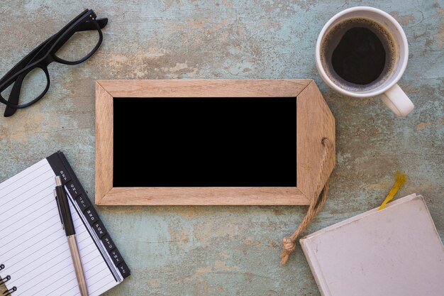 An overhead view of wooden slate; coffee and stationeries on an old grunge backdrop