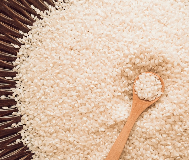 Overhead view of wooden spoon on white rice grains