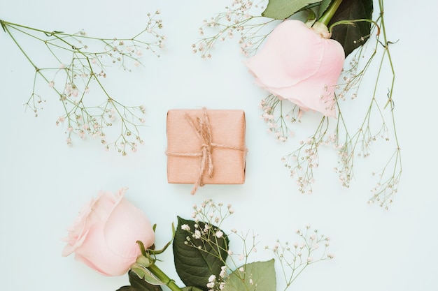 An overhead view of wrapped gift box with flowers on blue colored background