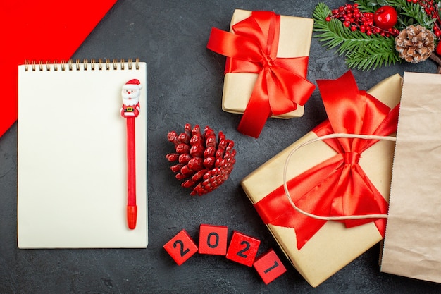 Overhead view of xsmas mood notebook with pen conifer cones and gift fir branches numbers on dark table