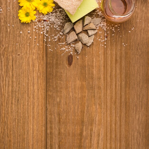 노란색 꽃의 오버 헤드보기; 소금; 돌; 스펀지; 나무 질감 배경 수 세미와 꿀 병