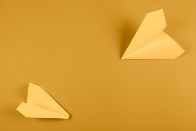 Free photo an overhead view of yellow paper airplane on bright colored background