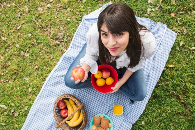 Вид сверху молодой женщины, показывая свежие фрукты в руке