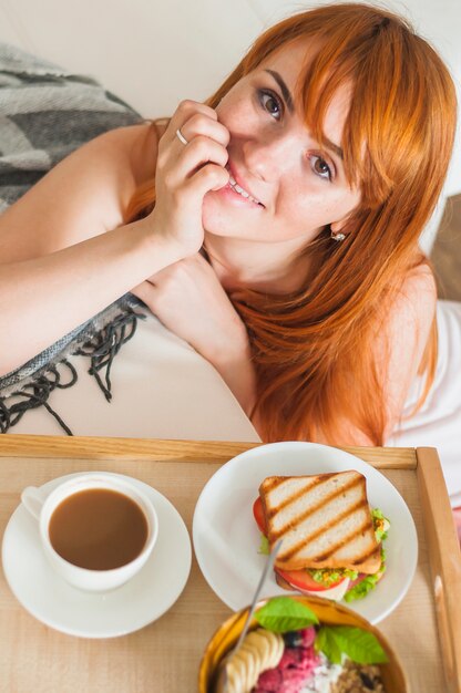 An overhead view of young woman with breakfast on wooden tray