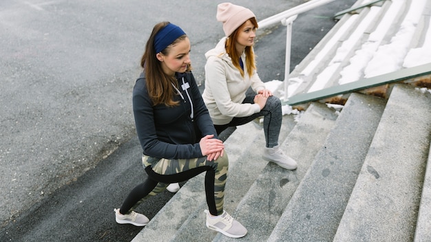 An overhead view of young women stretching their legs on staircase