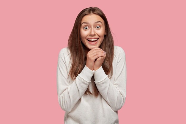 Overjoyed beautiful brunette posing against the pink wall