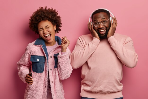 Overjoyed ethnic couple have good mood, relax together and dance to cool music