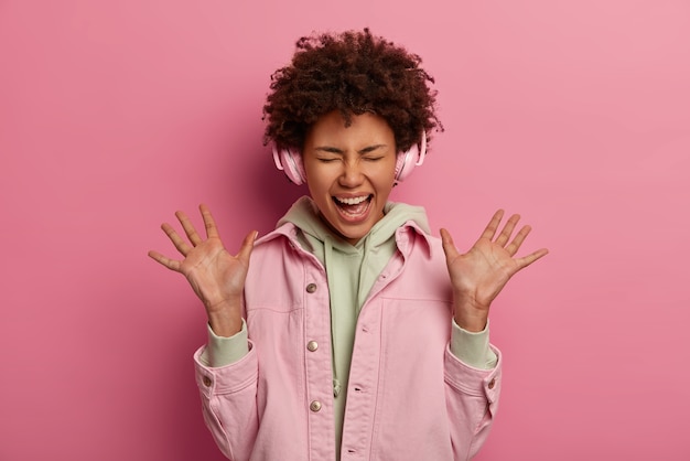 Overjoyed ethnic woman raises palms, exclaims positively