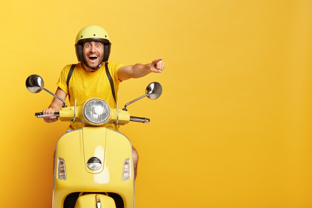 黄色いスクーターを運転するヘルメットを持つ大喜びの男