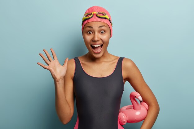 Overjoyed happy female swimmer raises palm, shouts loudly