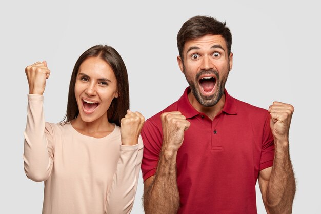 Overjoyed two woman ans man raise fists with triumph, have successful deal