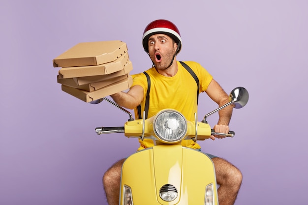 Overload busy deliveryman driving yellow scooter while holding pizza boxes