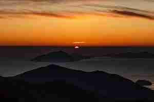 Foto gratuita affacciato su una silhouette di montagne nel mare durante il tramonto