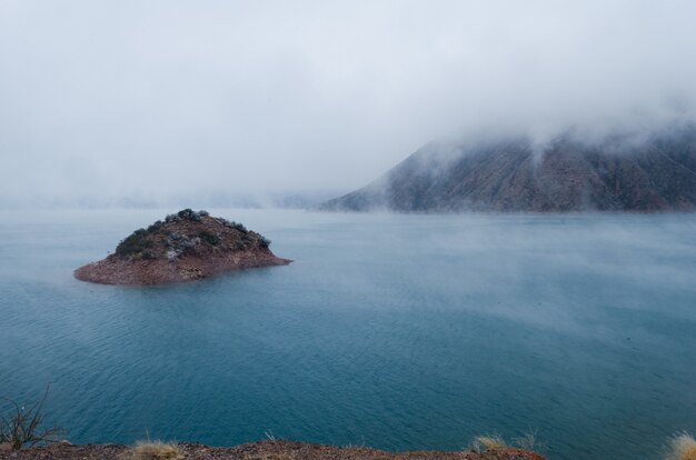 Overlooking view of a small island with a mountain covered with fogs during winter