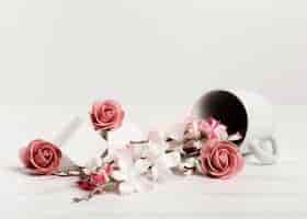 Foto gratuita tazza rovesciata con rose e cubi bianchi