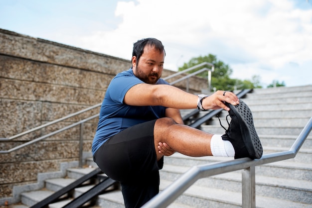 Бесплатное фото Мужчина с избыточным весом тренируется на лестнице на открытом воздухе
