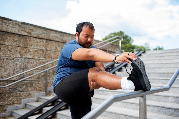Мужчина с избыточным весом тренируется на лестнице на открытом воздухе