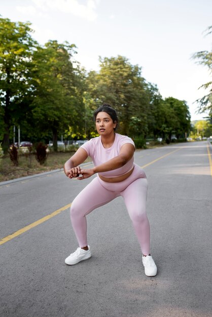Женщина с избыточным весом тренируется на открытом воздухе