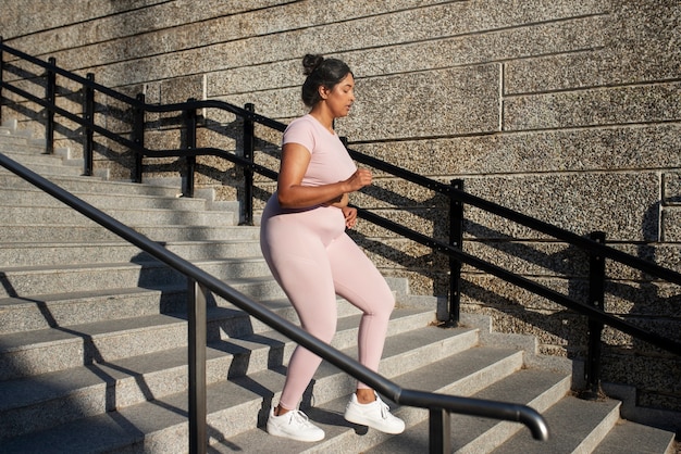 Женщина с избыточным весом тренируется на лестнице на открытом воздухе