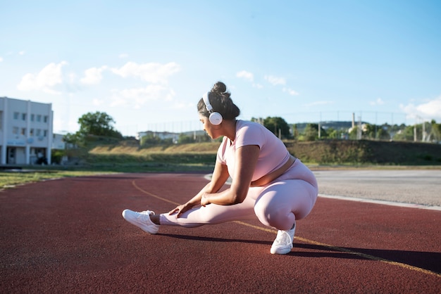 Overweight woman working out while listening to music on headphones