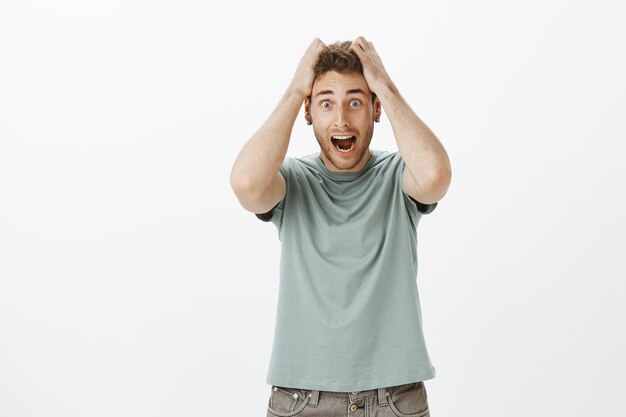 overwhelmed funny european man in casual t-shirt, pulling out hair and screaming, being fed up and over emotional, standing sick and tired