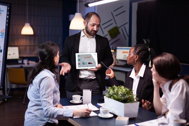 Overworked businessman showing financial graphs presentation using tablet brainstorming company ideas