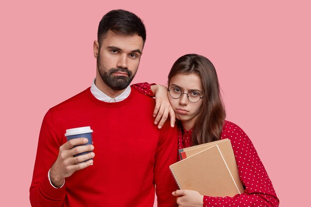과로 한 여자와 남자는 슬픈 표정을 짓고, 메모장을 들고, 테이크 아웃 커피를 마시고, 빨간 옷을 입고
