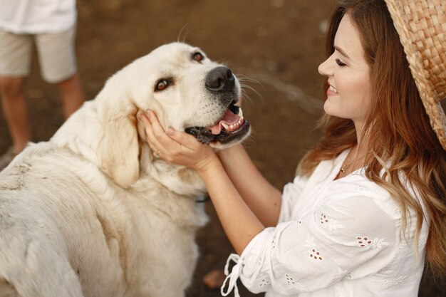 Owner and labrador retriever dog in a yard. Woman in a white dress. Golden retriever.